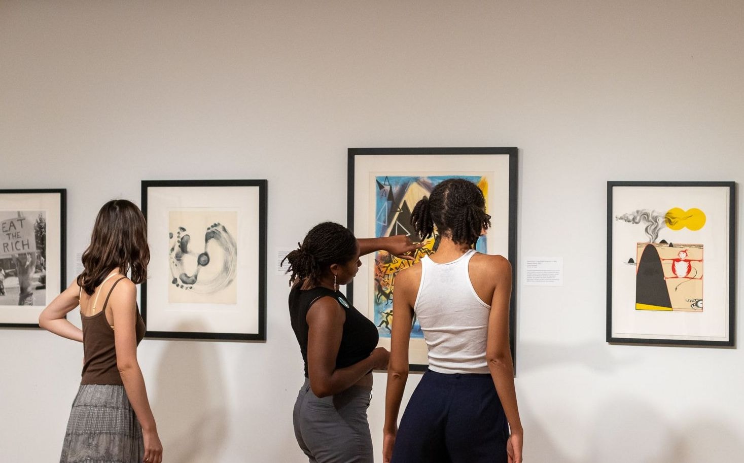 Three people look at the Art Loan collection. 