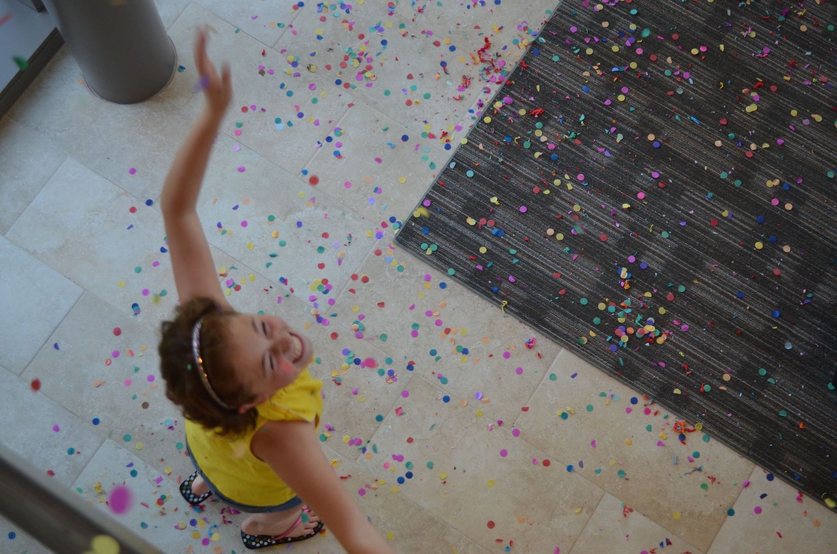 Young girl looking up at confettis falling down, in the entrance at the Gund Gallery