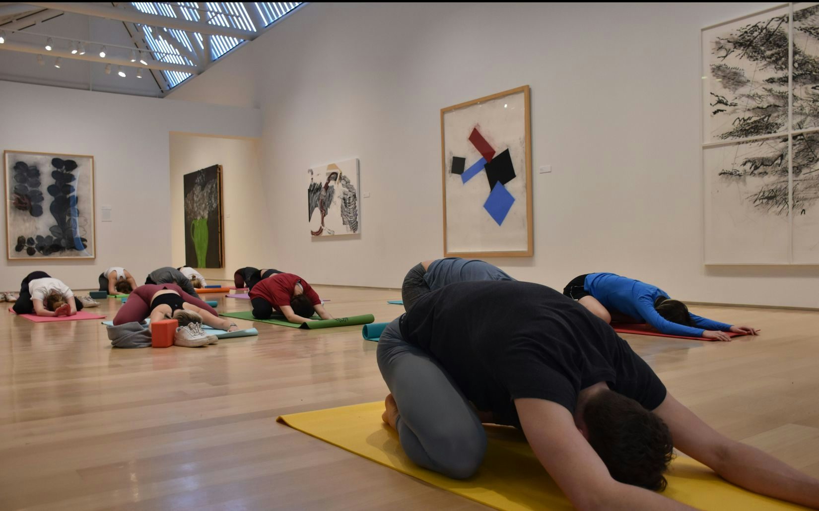 Several people are in Child's Pose during Yoga in the Gallery.