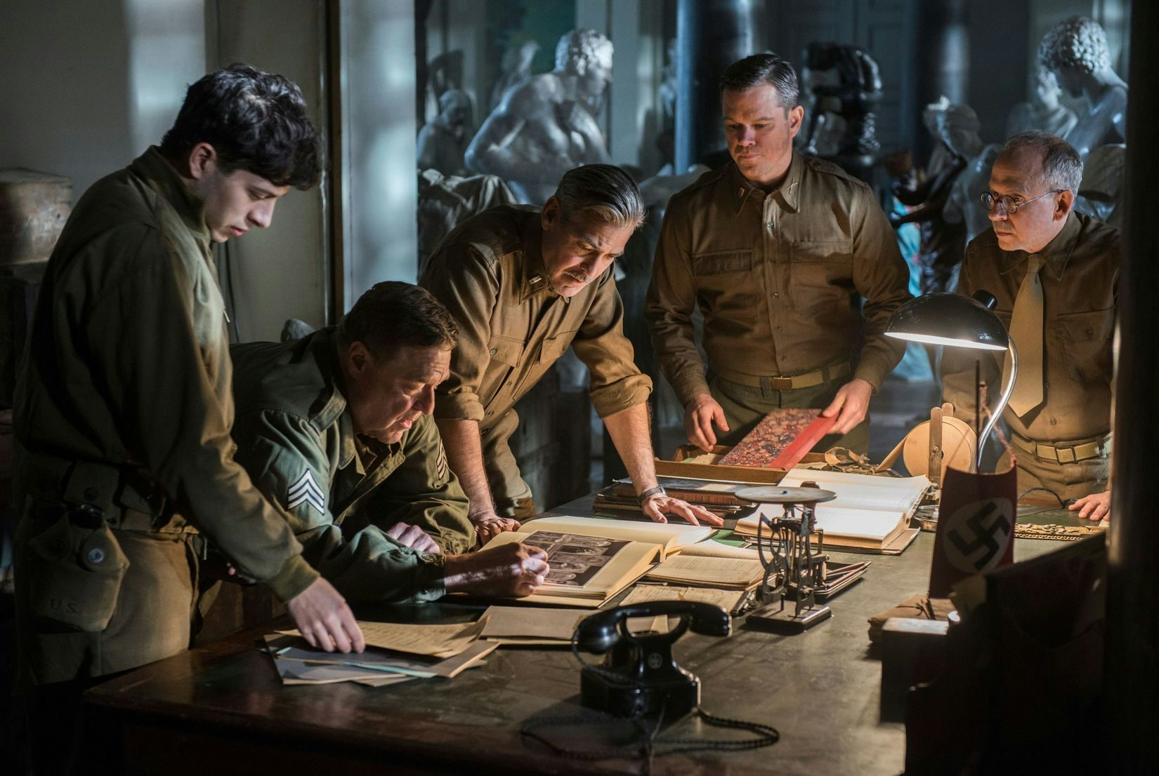 A group of the monuments men / soldiers around a table in The Monuments Men.